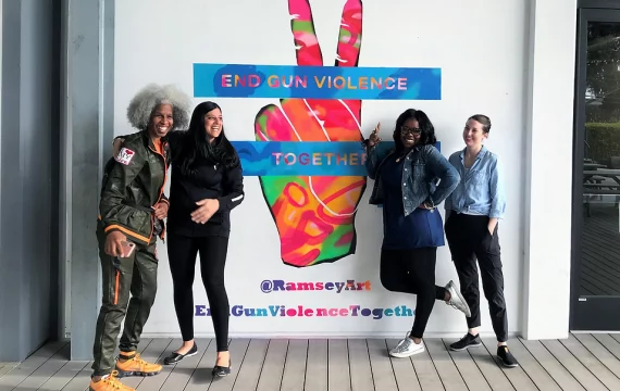 Four women standing in front of a peace sign.